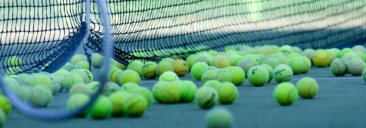 Tennisbälle liegen vor dem Netz auf dem Tennisplatz